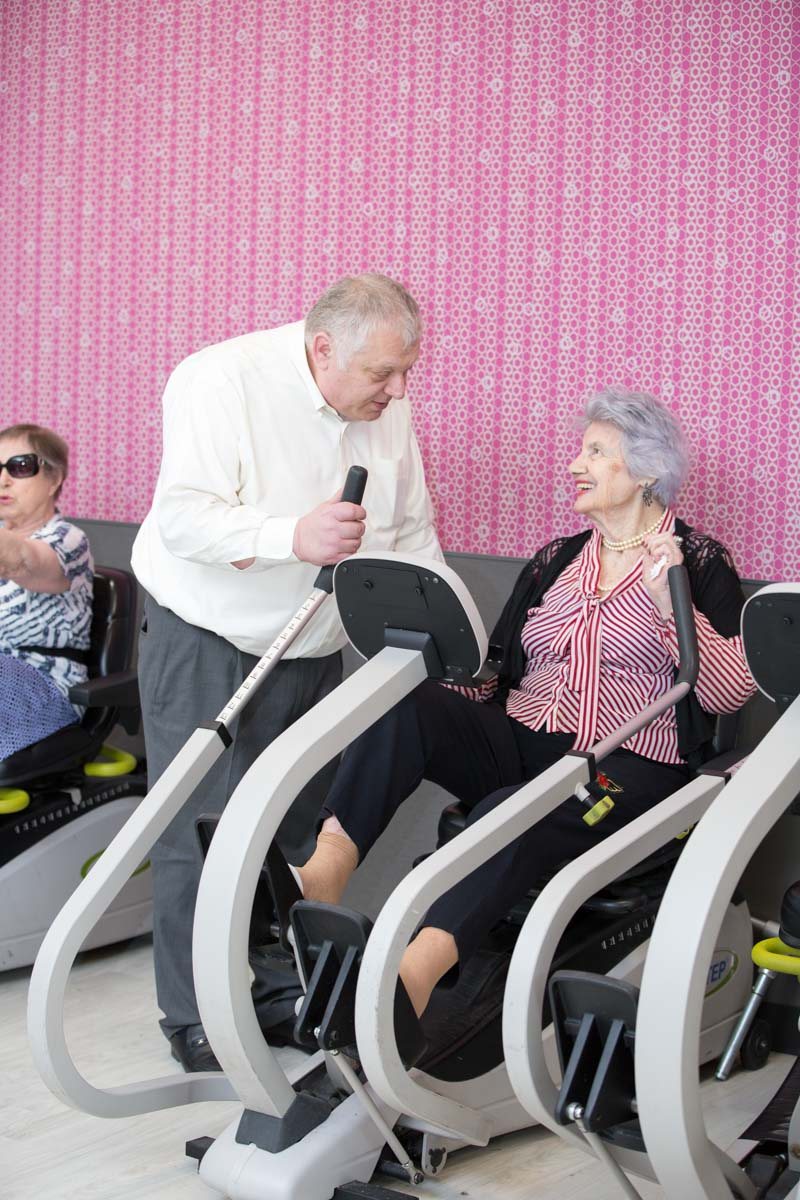 Therapist helping elderly woman to use the cycling machine for exercise to counteract diseases and to be the same after a stroke.