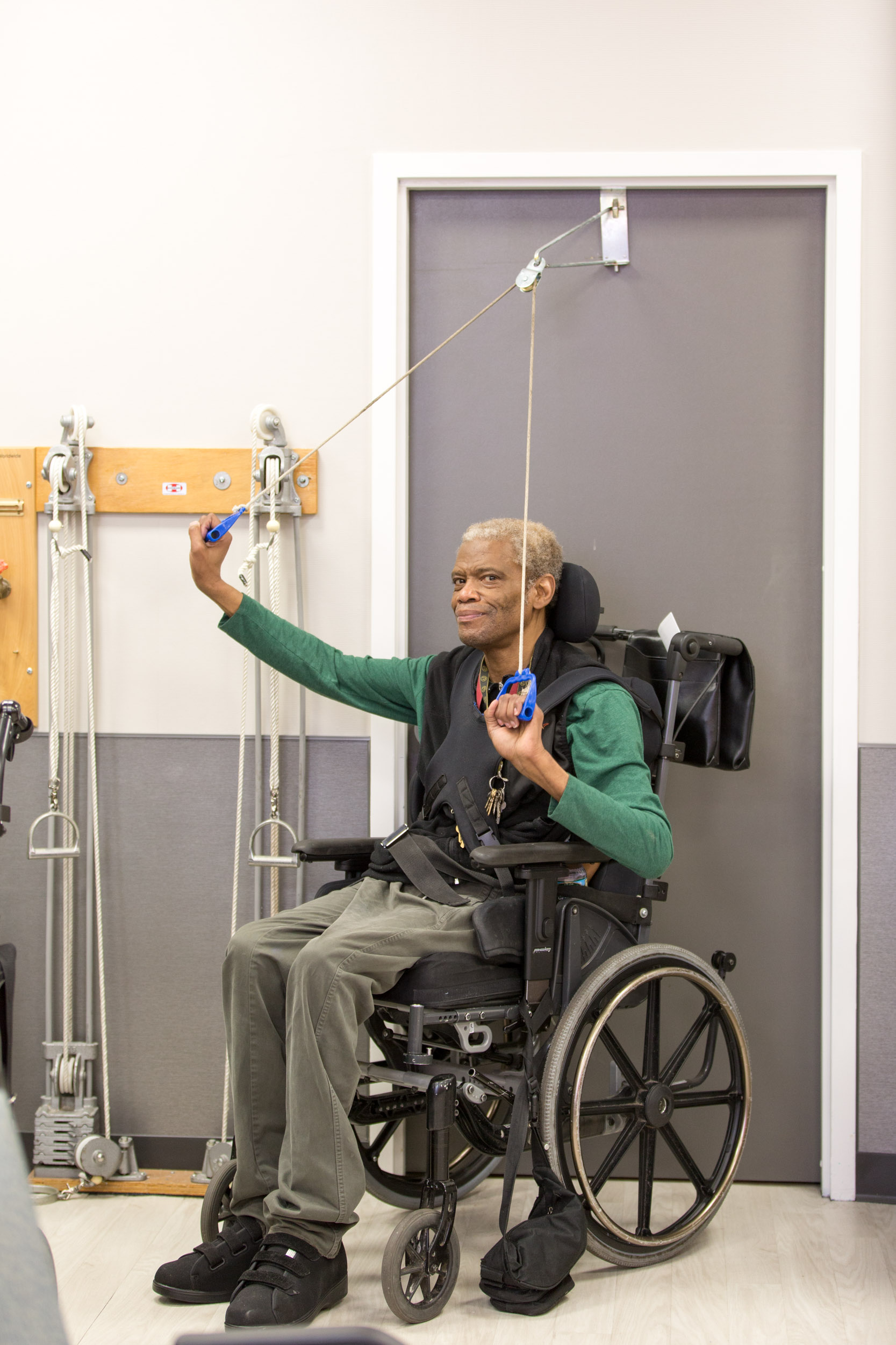 Senior black man sitting on a wheel chair and doing exercise as a part of physical therapy at Fairview ADC.