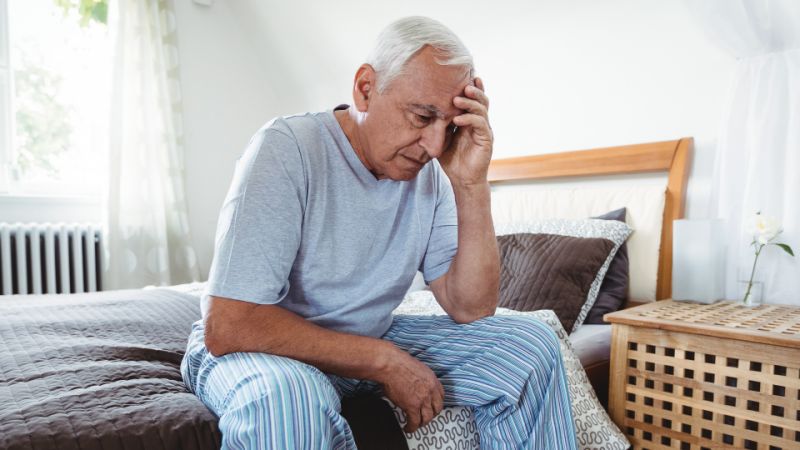 Stressed elderly man sitting on bed. Stress shortens life.