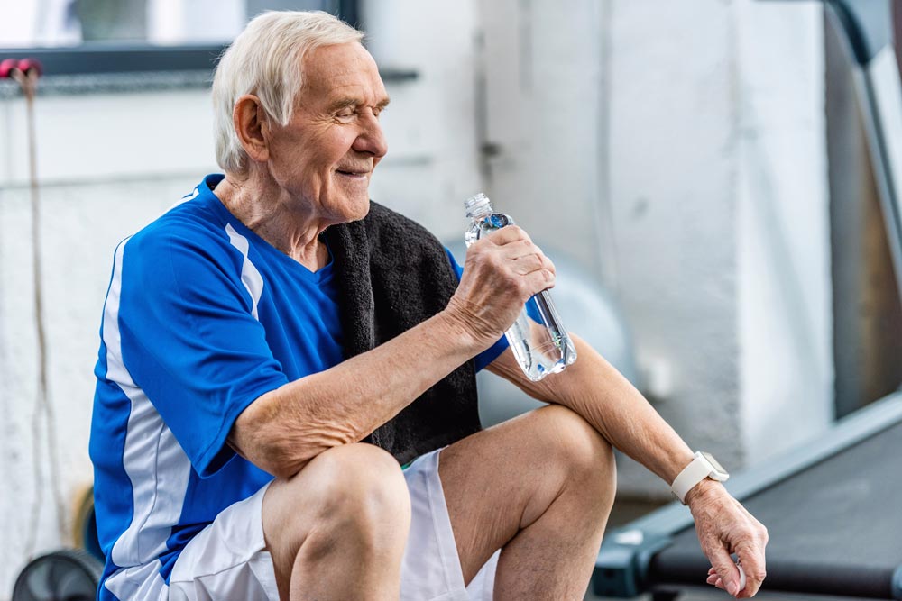 Senior man drinking water after physical therapy to prevent falls