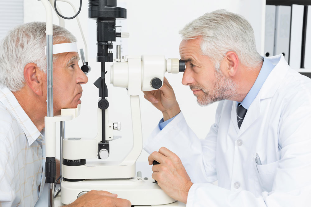 senior doctor examining elderly man's eyes suffering from blurry vision