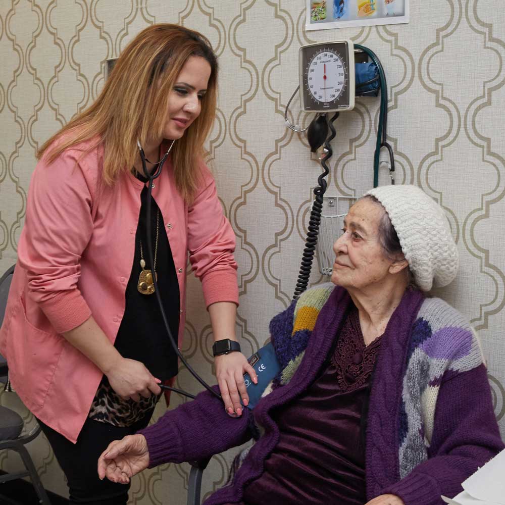 Nurse checking blood pressure of an elderly woman to stop atherosclerosis progress
