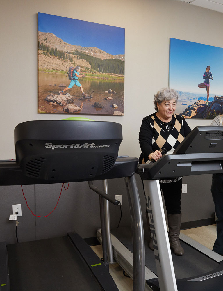 Elderly woman doing exercise on treadmill alone maintaining her independence and fitness to treat Sciatic Back Pain.