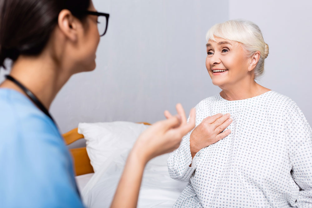 Elderly woman suffering from excess mucus touching chest while talking to the nurse