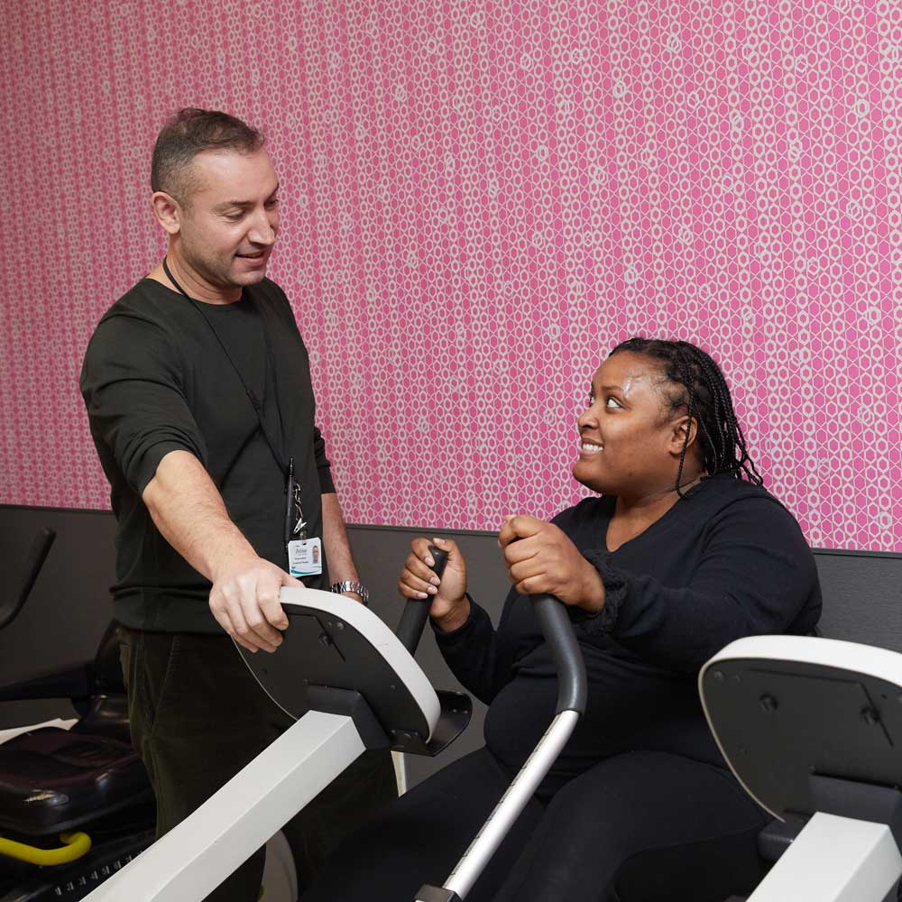 Male nursing staff helping black woman facing complications of arthritis in getting physical therapy.