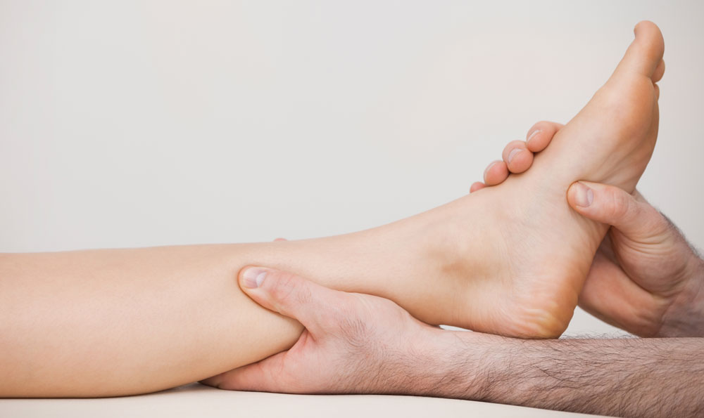 Chiropodist providing podiatry for diabetic patient by holding the ankle