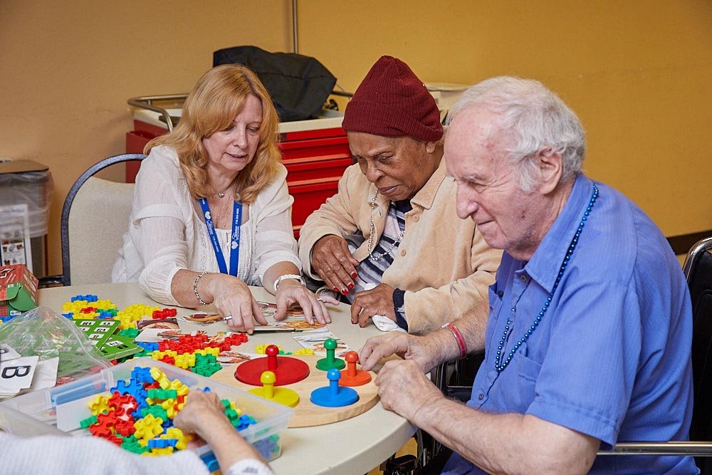 Senior man and woman suffering from untreated medical illness playing mind games with rehabilitation therapist.