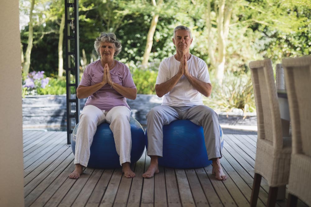 Senior couples meditating on exercise balls. Chair yoga benefits for seniors.