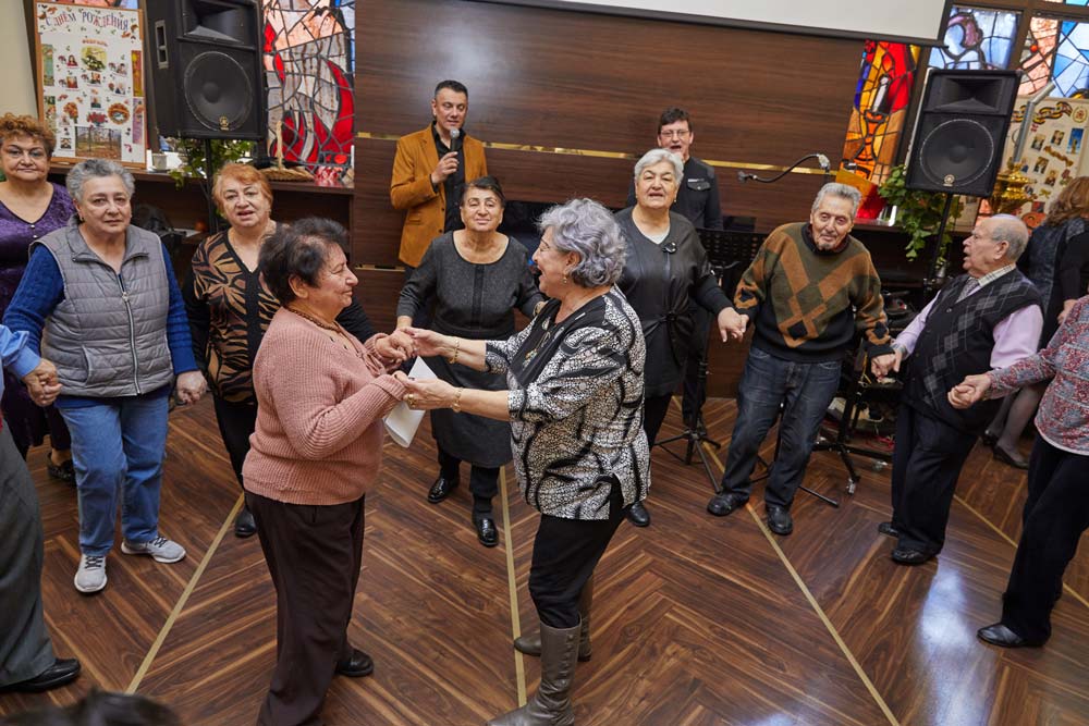 Senior woman doing couple dance to strengthen the heart while others are holding each others hands.