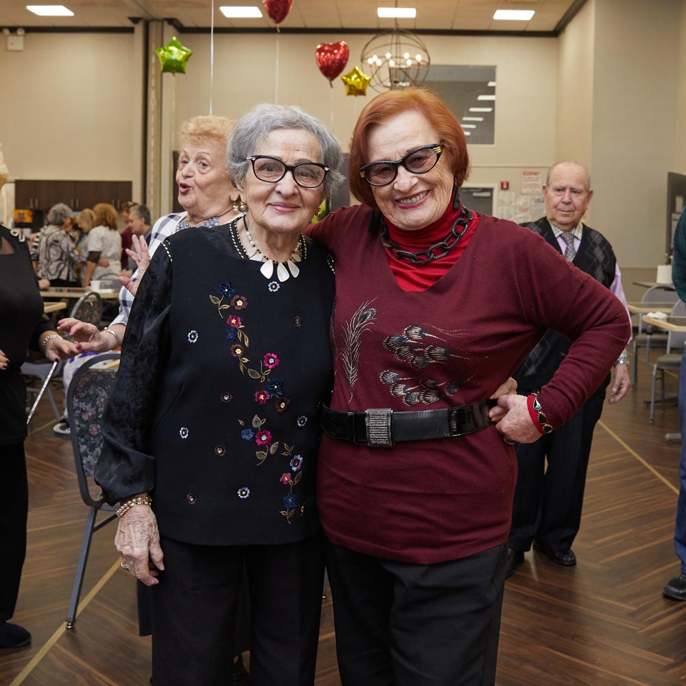 Two senior women socialization with each other during a recreation event.
