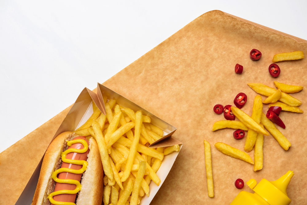 Close up of a hotdog burger and fries. Excessive use of such foods can clog arteries.
