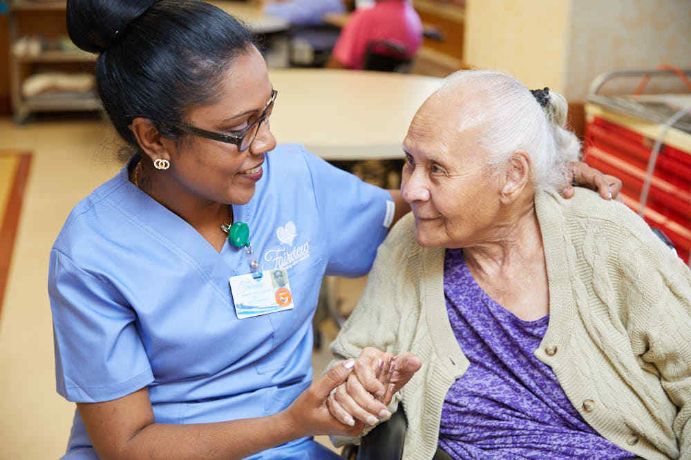 Nurse holding hands of a senior woman suffering from hearing loss.