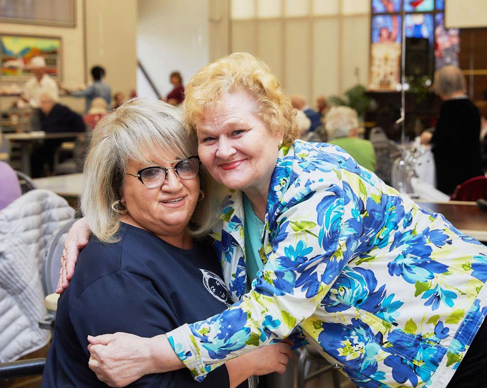 Happy senior women hugging social worker for seniors.