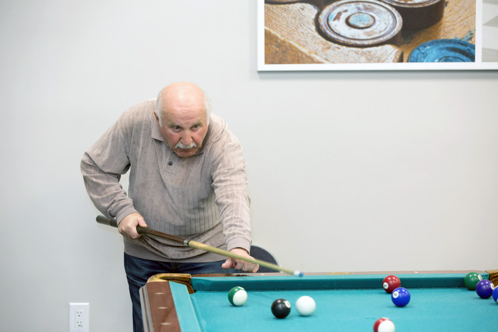 Senior man with early signs of dementia playing pool.