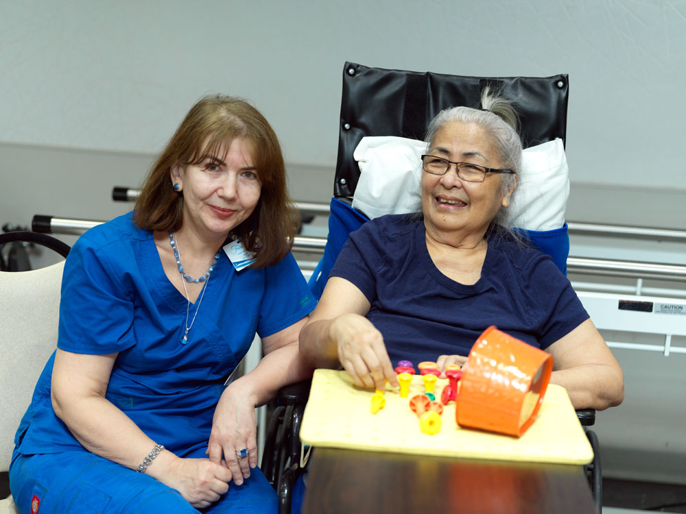 Senior woman suffering from Decline in Neurological Function playing puzzles with a nurse to slow down the decline.