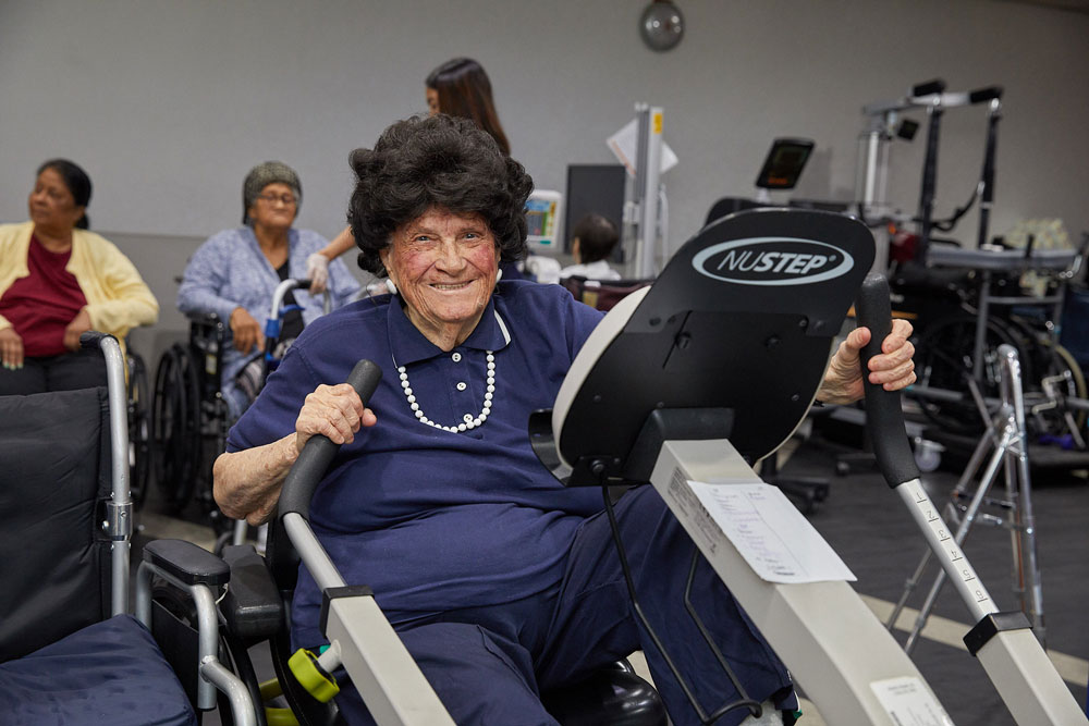 Senior woman with the age of over 70 doing strength training exercise on a machine.