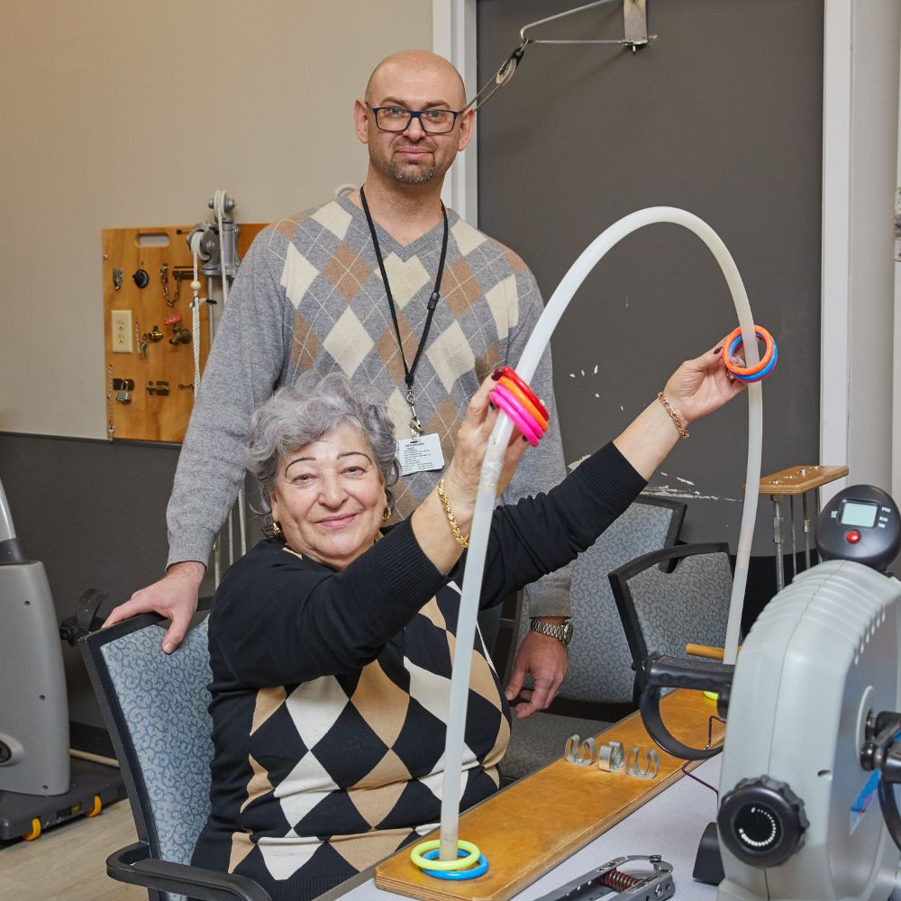 Physical therapist helping smiling senior woman with exercise to recover from Post-Hospital Weakness and Fatigue.