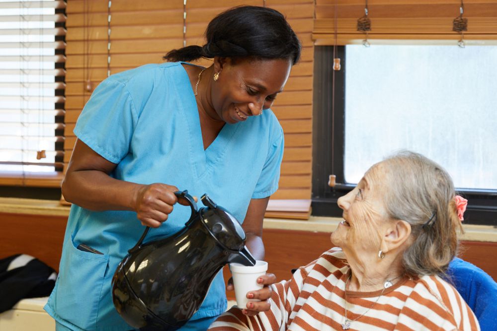 Nursing pouring coffee for an elderly. Recreation activities are crucial in recovery.
