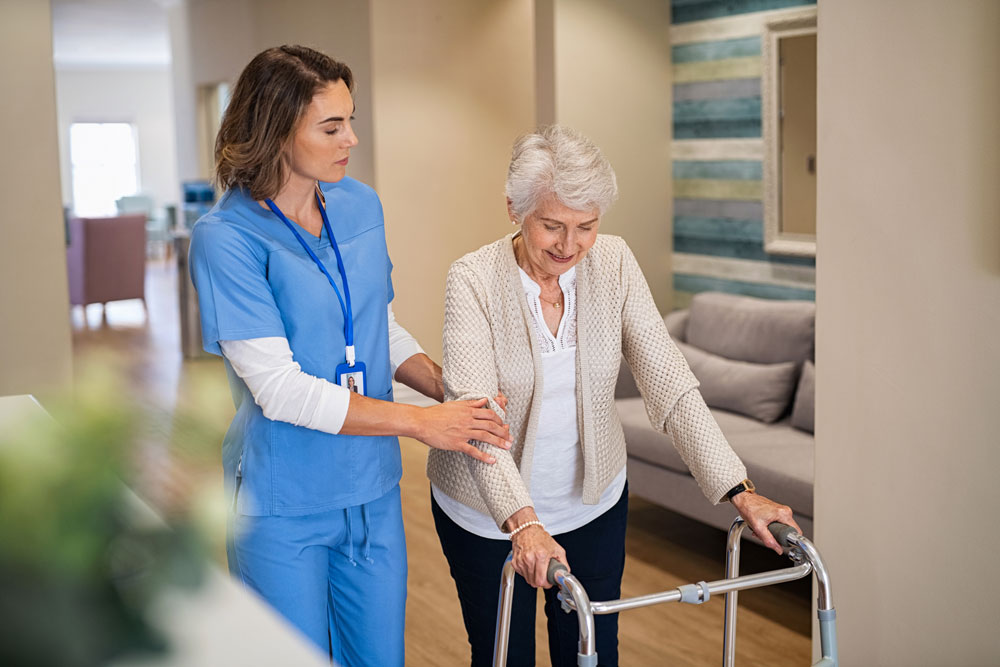 Nurse helping an elderly woman in walking as part of physical therapy suffering from Neuropathy In Legs and Feet.