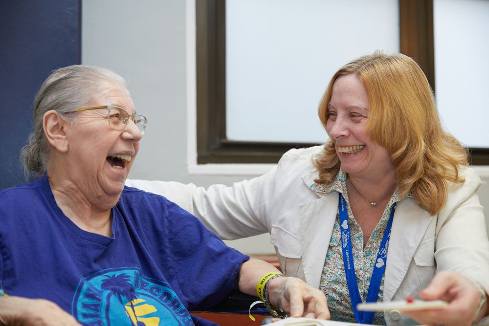 Senior woman laughing with therapist during recreation therapy to live longer.