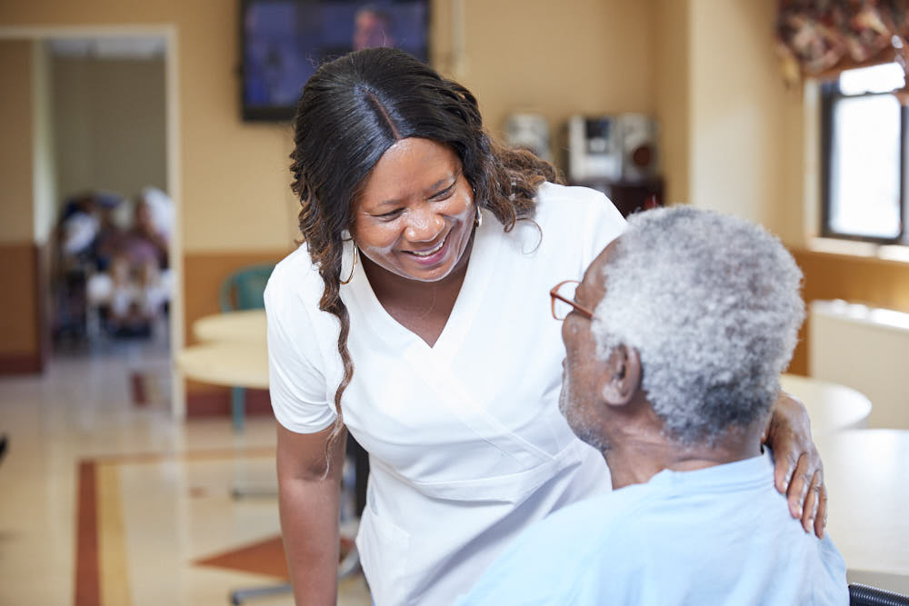 Smiling black nurse with an elderly patient suffering from sudden inability to speak.