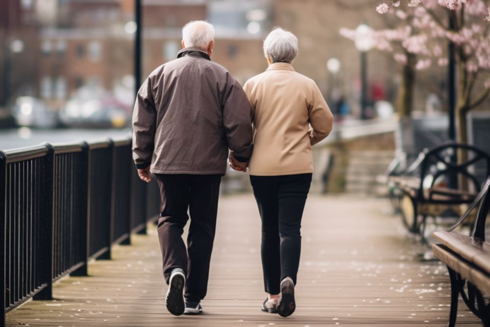 Elderly couple holding hands and walking to avoid chronic stress.