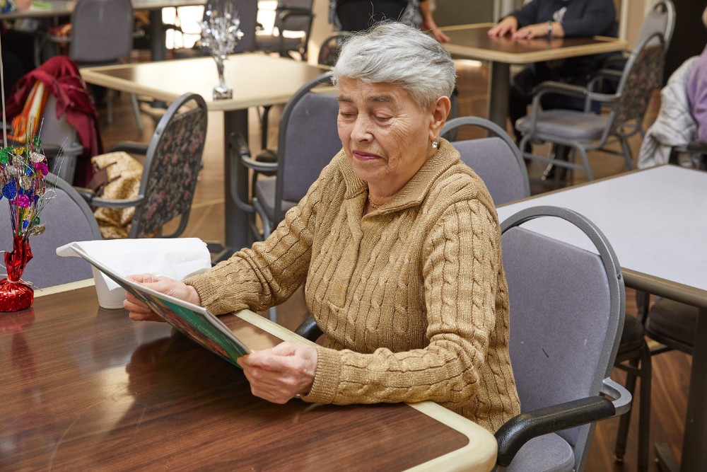 Elderly woman reading magazine in early morning to keep brain sharp.